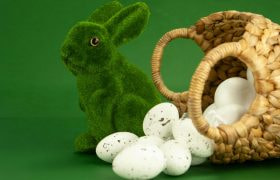 Groene paashaas gemaakt van gras en een mandje met witte eitjes