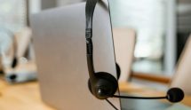 Achterkant van een laptop, waar een zwarte headset aan hangt