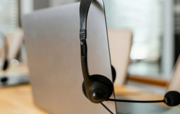 Achterkant van een laptop, waar een zwarte headset aan hangt