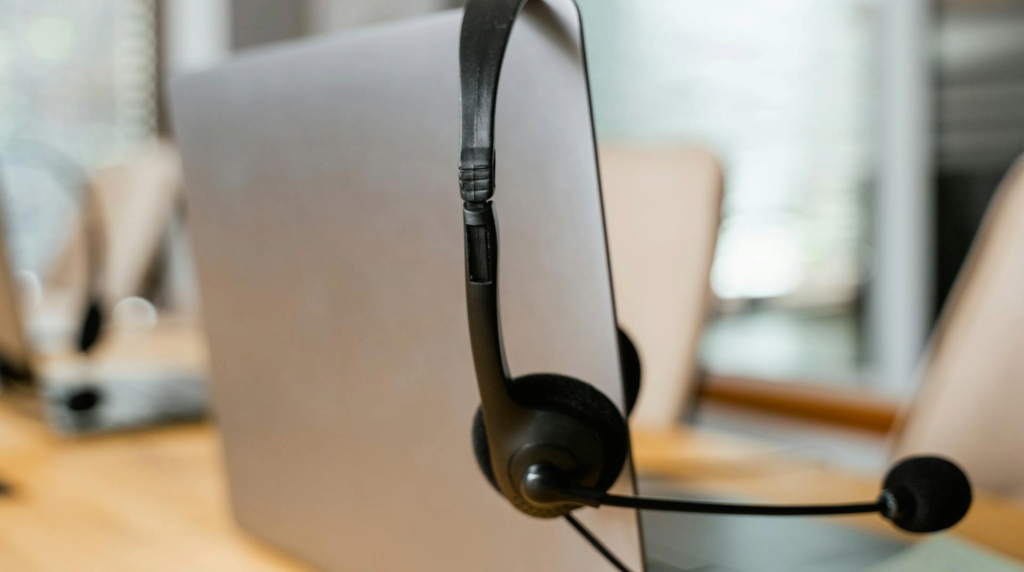 Achterkant van een laptop, waar een zwarte headset aan hangt