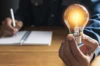 A hand holding an illuminated light-bulb.