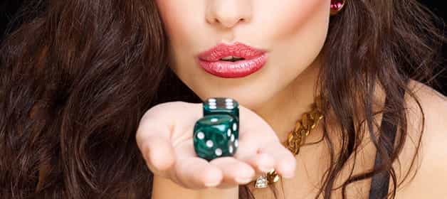 Uma mulher a soprar ar para uma mão segurando dois dados de craps.