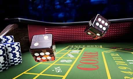 two dice in the air above a craps table in a land-based casino