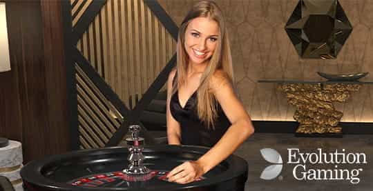 A croupier from the Evolution Gaming Live staff sitting behind a roulette table.
