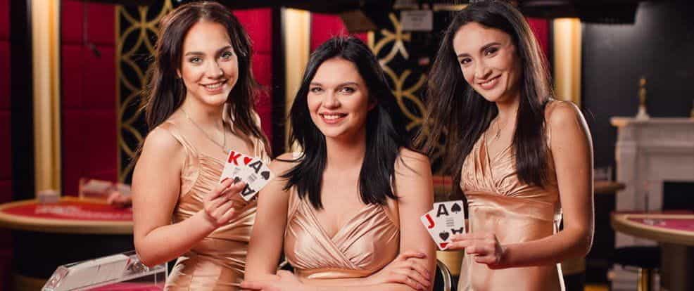 Three female live dealers holding playing cards.