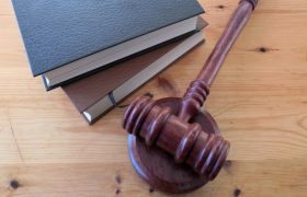 Ciocan de judecător și cărți de lege pe o masă de lemn