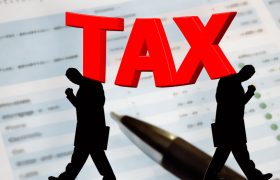 Ilustrație cu cuvântul TAX peste un document financiar