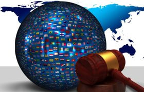 Un glob acoperit cu steaguri ale țărilor alături de un ciocan judecătoresc.