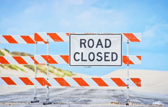 Un drum cu o barieră și text Drum închis