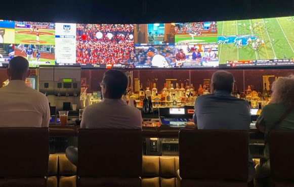 Oameni într-un bar urmărind mai multe evenimente sportive