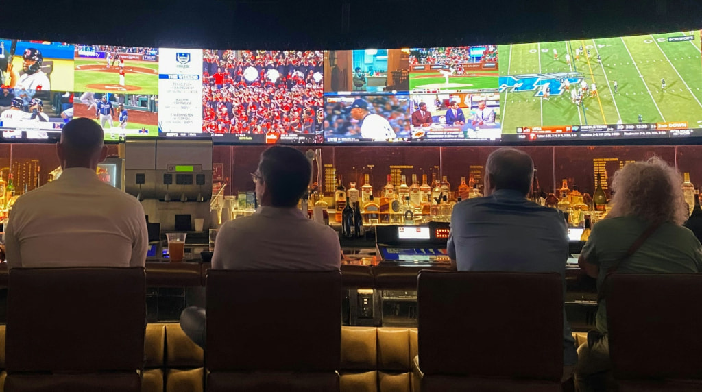 Oameni într-un bar urmărind mai multe evenimente sportive