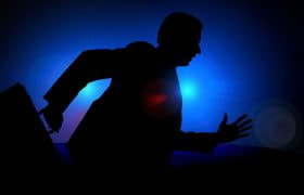 Siluetă de bărbat alergând cu o servietă în întuneric