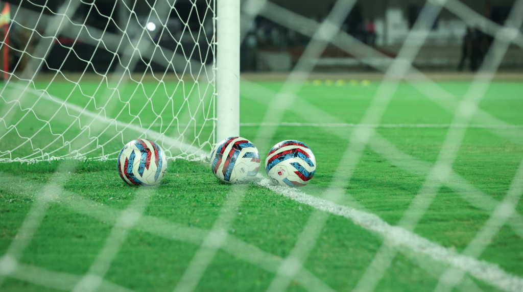 Trei mingi de fotbal în apropierea unei porți de fotbal