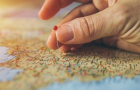 Mână care plasează un ac pe hartă