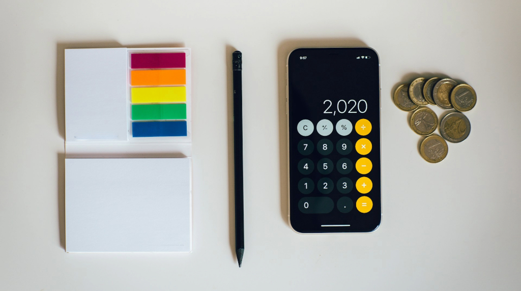 Bilete adezive pentru notițe, un creion, un calculator și câteva monede