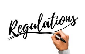 Mână scrie cuvântul reglementări