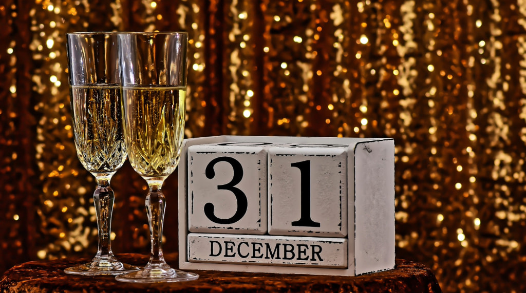 Două pahare de șampanie lângă un calendar cu 31 decembrie
