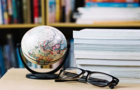 Globul pământesc pe un birou, cu un teanc de foi