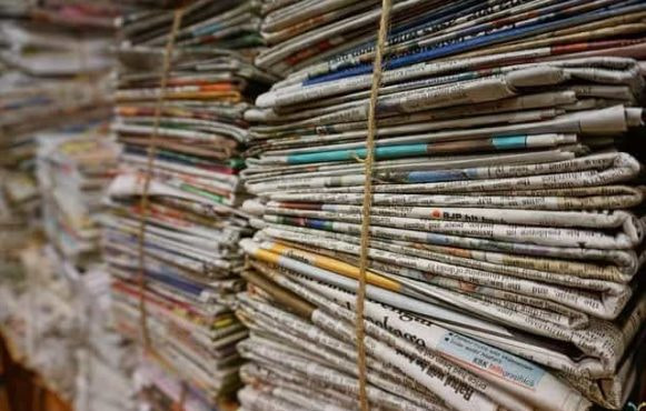 Stacks of newspapers bundled together with rope.