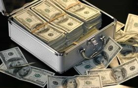 A silver briefcase overflowing with $100 US dollar bills.