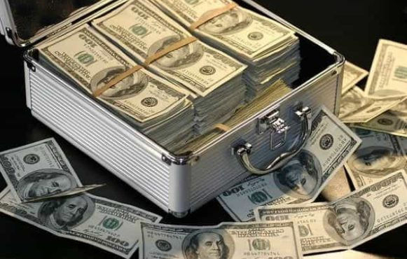 A silver briefcase overflowing with $100 US dollar bills.