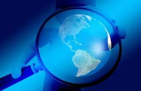 A magnifying glass behind held by a figure in a cap as it hovers over and magnifies Planet Earth.