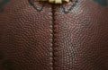 A very close up shot of an American football, featuring its iconic ridge and pigskin brown texture.