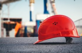 A worker’s hard hat helmet sitting on the ground of a construction site.
