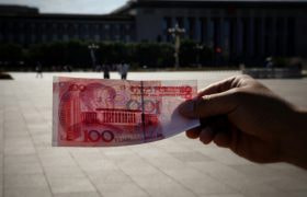 A hand holding a 100-yuan banknote