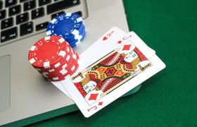 An image showing a strong hand in a game of online poker, chips and a laptop.