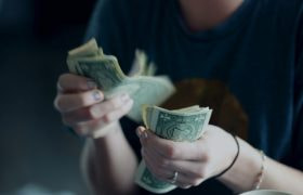 A person counting small dollar bills