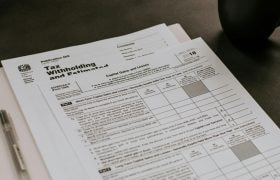 Folder filled with IRS forms beside a cup of coffee