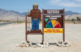 Smokey the Bear holding a fire warning sign