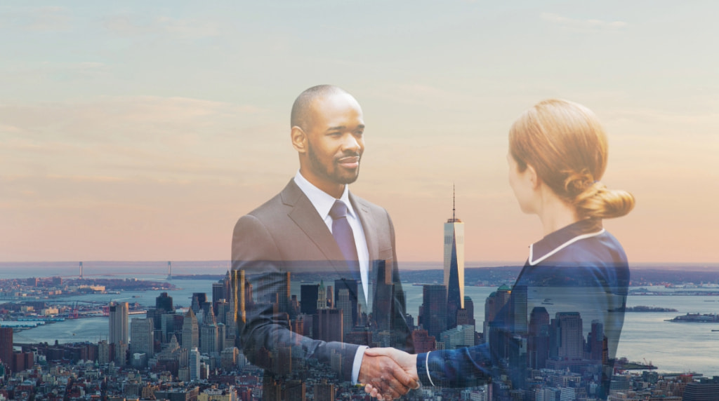 A businessman and businesswoman shaking hands with view of Manhattan in New York in the background.