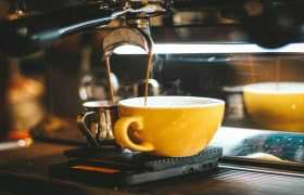 A close-up of an espresso machine pouring coffee into a yellow cup