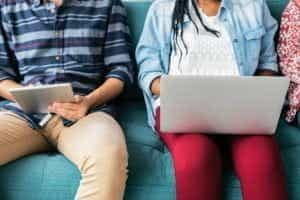 People sitting and using a computer and handheld tablet.