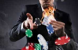 A man holding flaming cards and chips.