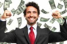 A man in a suit smiling as it rains cash.