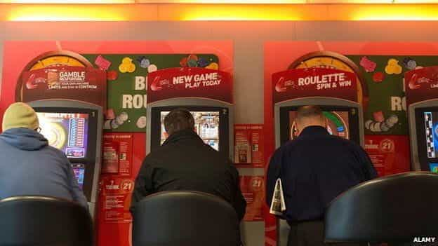 Three players sitting at fixed-odds betting terminals.