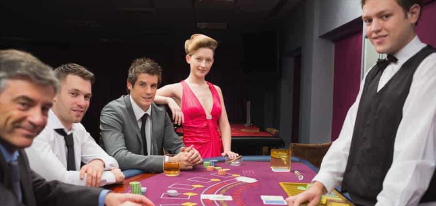 A croupier and casino players smiling at the camera.