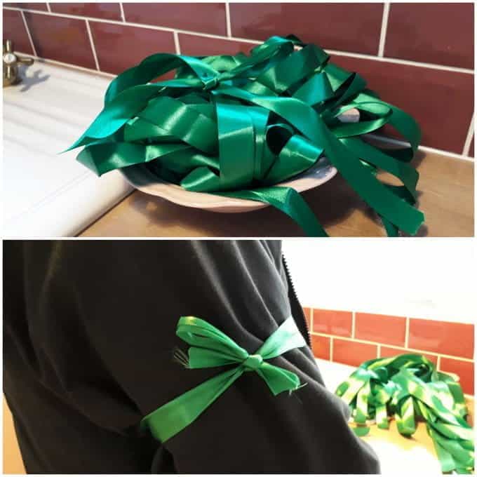 A bowl of green ribbons and a green ribbon tied around someone's arm.