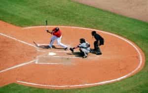 A baseball batter swinging at a pitch, with catcher and umpire behind him.