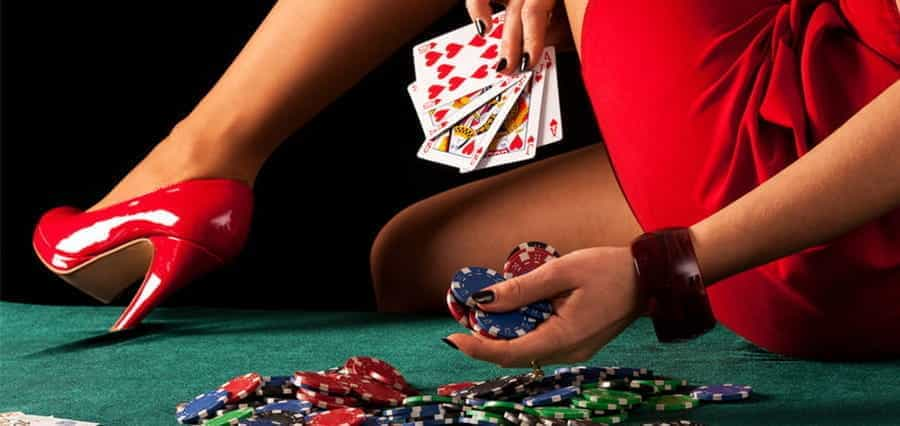 A woman holding casino chips and cards, while placing her high-heeled foot on a casino table.