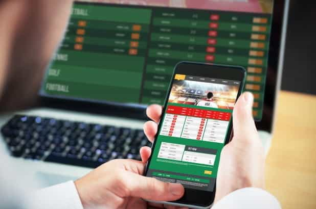 Sports betting shown on laptop and mobile phone.