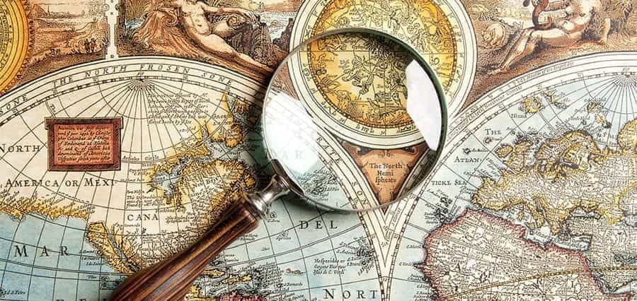 Ancient world maps and a magnifying glass.