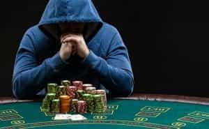 A faceless gambler sits at a poker table.