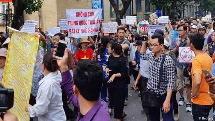 Vietnamese protestors protest the new SEZ laws with picket signs.