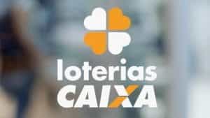 The logo for “Loterias Caixa” in front of a blurry, neutral colored background. 