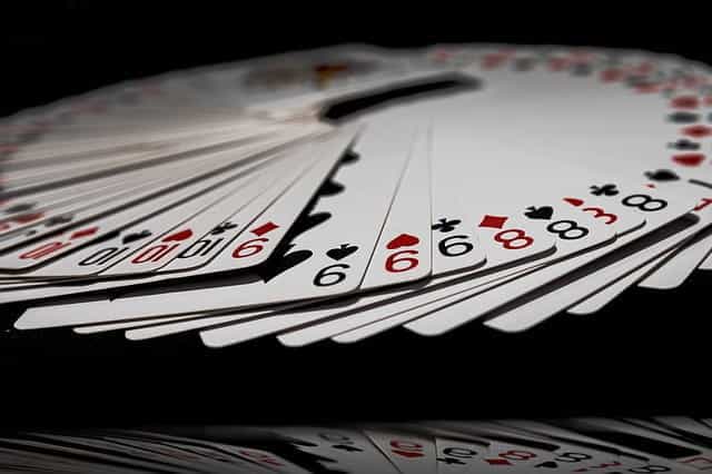 Close up of a deck of cards spread out on a black surface.