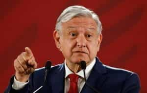 Mexico’s President, Andrés Manuel López Obrador, speaks in front of a red curtain.